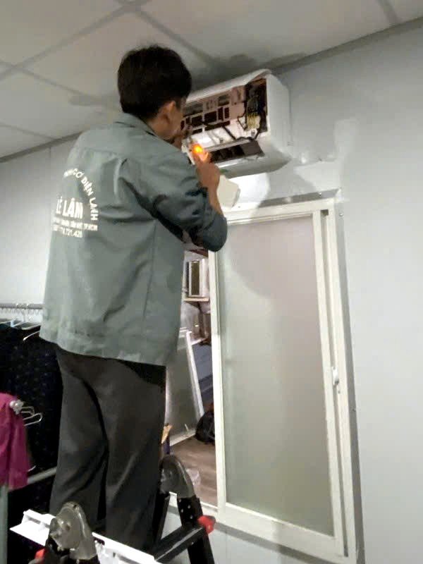 Kỹ thuật viên tháo vỏ dàn lạnh, dùng đèn soi kiểm tra điểm rò gas