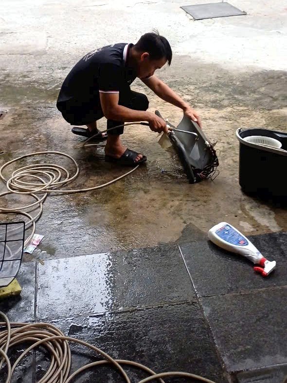 Kỹ thuật viên xịt rửa linh kiện dàn lạnh máy lạnh bằng nước áp lực