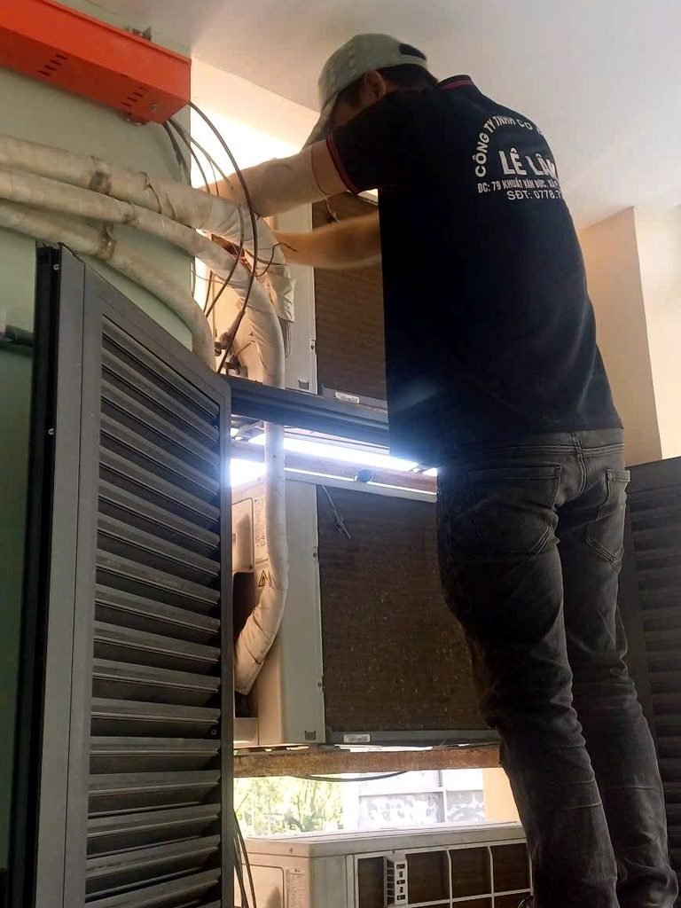 Kỹ thuật viên kiểm tra cụm dàn nóng máy lạnh, đường ống gas và dây điện